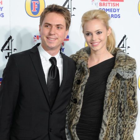 joe in a black suit, hannah wearing a black dress with a leopard print coat on the red carpet 